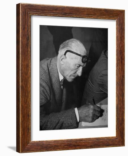 Swiss Architect Le Corbusier Leaning Down to Write with His Glasses Pushed Back on His Forehead-null-Framed Photographic Print