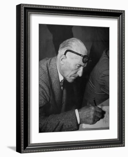 Swiss Architect Le Corbusier Leaning Down to Write with His Glasses Pushed Back on His Forehead-null-Framed Photographic Print