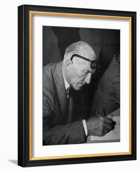 Swiss Architect Le Corbusier Leaning Down to Write with His Glasses Pushed Back on His Forehead-null-Framed Photographic Print