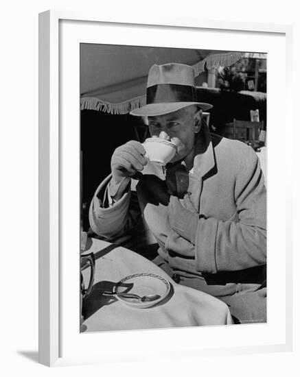 Syndicated Columnist Walter Winchell Clad in Overcoat and Gloves Drinking Coffee in Outdoor Patio-Alfred Eisenstaedt-Framed Premium Photographic Print