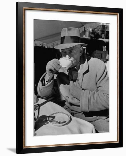 Syndicated Columnist Walter Winchell Clad in Overcoat and Gloves Drinking Coffee in Outdoor Patio-Alfred Eisenstaedt-Framed Premium Photographic Print