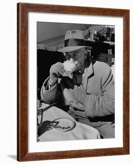 Syndicated Columnist Walter Winchell Clad in Overcoat and Gloves Drinking Coffee in Outdoor Patio-Alfred Eisenstaedt-Framed Premium Photographic Print