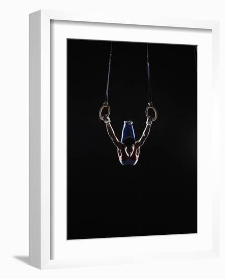 Teenage (16-17) Male Gymnast Practicing on Rings against Black Background-Thomas Barwick-Framed Photographic Print