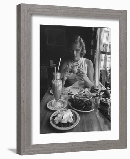 Teenaged Girl Sitting in Drugstore Eating a Hamburger-Hank Walker-Framed Photographic Print