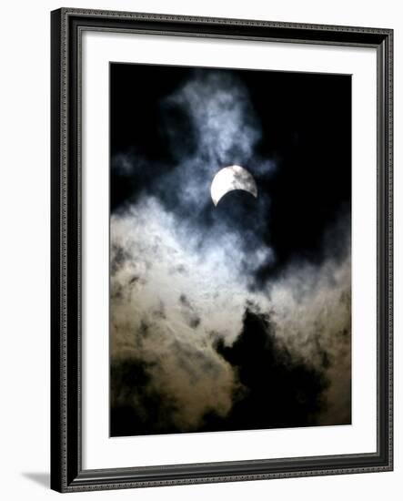 The Moon Partially Covers the Sun Behind the Clouds During a Partial Solar Eclipse-null-Framed Photographic Print