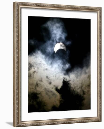 The Moon Partially Covers the Sun Behind the Clouds During a Partial Solar Eclipse-null-Framed Photographic Print