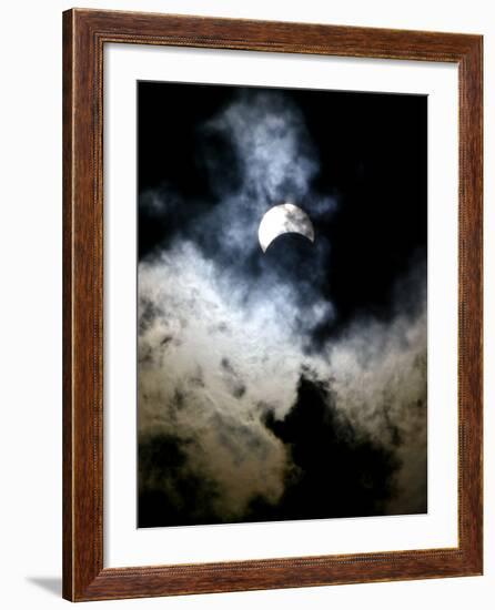 The Moon Partially Covers the Sun Behind the Clouds During a Partial Solar Eclipse-null-Framed Photographic Print