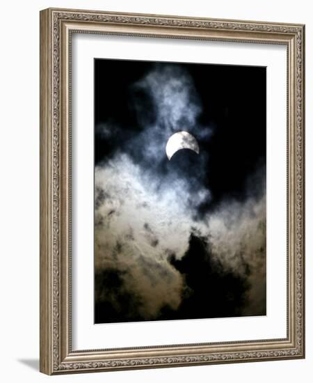 The Moon Partially Covers the Sun Behind the Clouds During a Partial Solar Eclipse-null-Framed Photographic Print