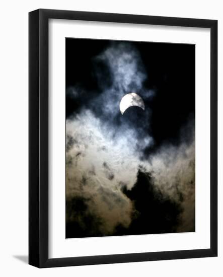 The Moon Partially Covers the Sun Behind the Clouds During a Partial Solar Eclipse-null-Framed Photographic Print