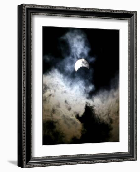 The Moon Partially Covers the Sun Behind the Clouds During a Partial Solar Eclipse-null-Framed Photographic Print