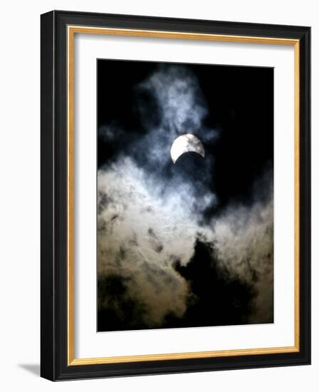 The Moon Partially Covers the Sun Behind the Clouds During a Partial Solar Eclipse-null-Framed Photographic Print