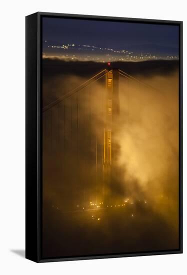 The North Tower Of The Golden Gate Bridge At Night With Fog Swirling In The Lights-Joe Azure-Framed Stretched Canvas