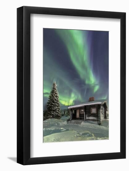 The Northern Lights (Aurora borealis) frame the wooden hut in the snowy woods, Pallas, Yllastunturi-Roberto Moiola-Framed Photographic Print