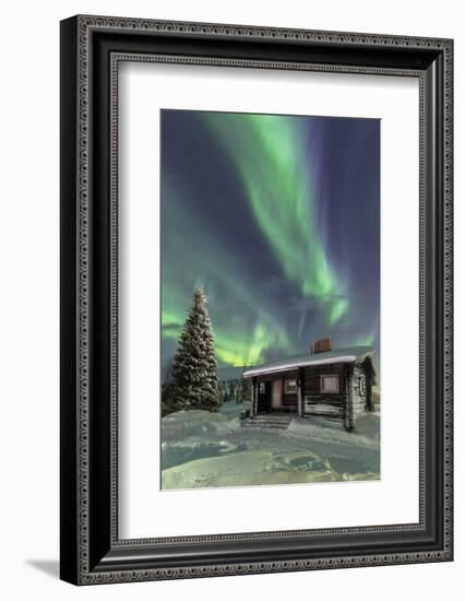 The Northern Lights (Aurora borealis) frame the wooden hut in the snowy woods, Pallas, Yllastunturi-Roberto Moiola-Framed Photographic Print