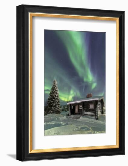 The Northern Lights (Aurora borealis) frame the wooden hut in the snowy woods, Pallas, Yllastunturi-Roberto Moiola-Framed Photographic Print