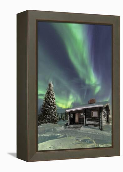 The Northern Lights (Aurora borealis) frame the wooden hut in the snowy woods, Pallas, Yllastunturi-Roberto Moiola-Framed Premier Image Canvas