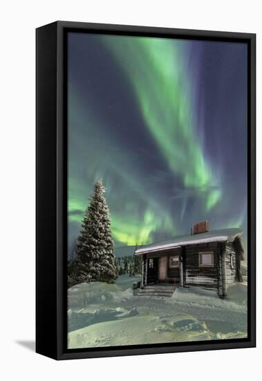 The Northern Lights (Aurora borealis) frame the wooden hut in the snowy woods, Pallas, Yllastunturi-Roberto Moiola-Framed Premier Image Canvas