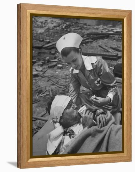 The Red Cross Nurse Trying to Help the Injured Man Eat and Drink-Allan Grant-Framed Premier Image Canvas