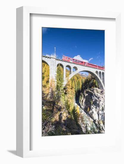 The red train on viaduct surrounded by colorful woods, Cinuos-Chel, Canton of Graubunden, Engadine,-Roberto Moiola-Framed Photographic Print