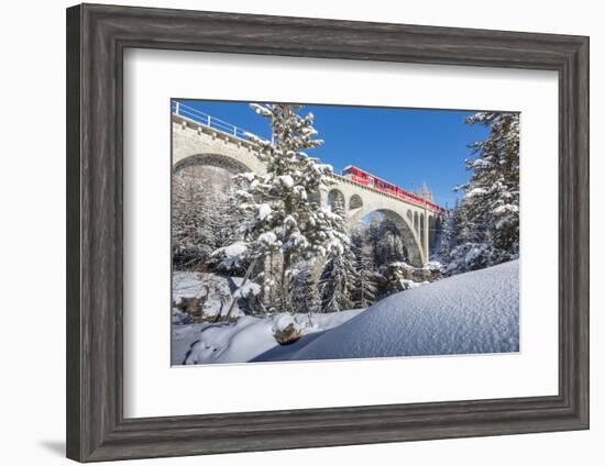 The red train on viaduct surrounded by snowy woods, Cinuos-Chel, Canton of Graubunden, Engadine, Sw-Roberto Moiola-Framed Photographic Print