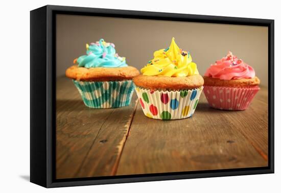 Three Different Colors Cupcakes On A Wooden Table, Blue, Yellow And Pink-pink candy-Framed Stretched Canvas