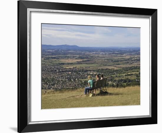 Three Girls Sitting on Bench Looking at View Over Bishops Cleeve Village, the Cotswolds, England-David Hughes-Framed Photographic Print