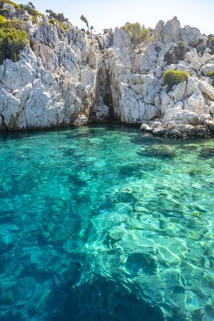 Turquoise colored crystal clear water at a rocky island