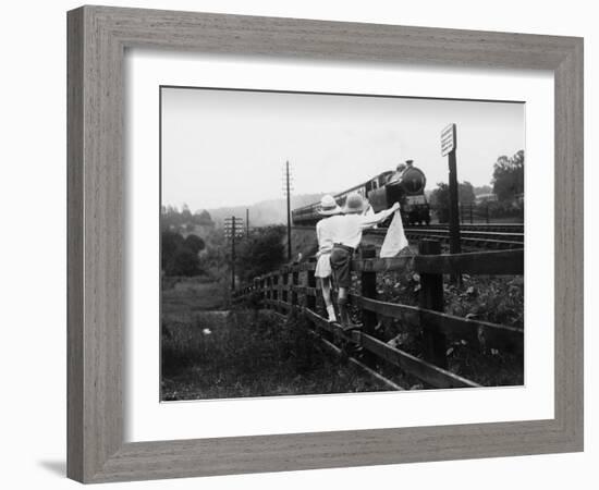 Two Children Stand on a Fence and Wave a Handkerchief at a Passing Steam Train-Staniland Pugh-Framed Photographic Print