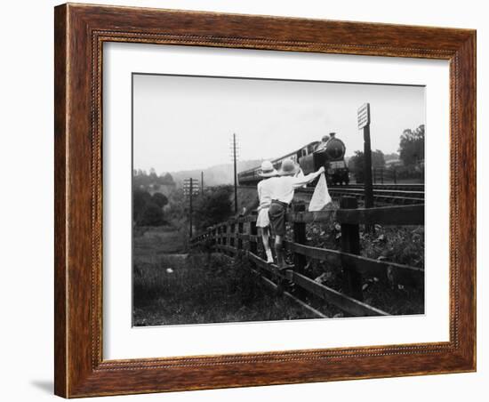 Two Children Stand on a Fence and Wave a Handkerchief at a Passing Steam Train-Staniland Pugh-Framed Photographic Print