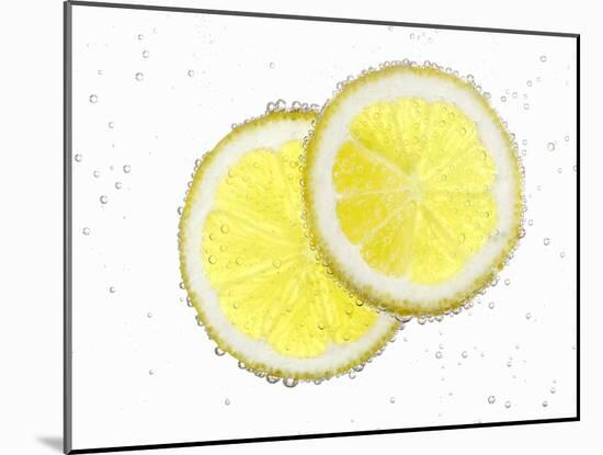 Two Lemon Slices in Water with Air Bubbles-Kröger & Gross-Mounted Photographic Print