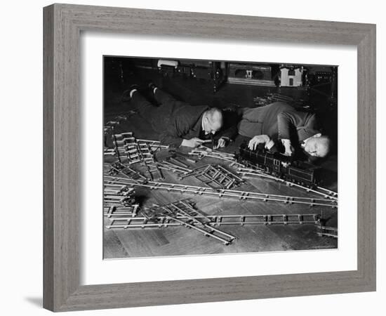 Two Men Lying on the Floor, Constructing a Railroad, at Toy Train Society-Alfred Eisenstaedt-Framed Photographic Print