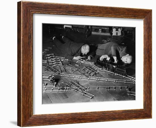 Two Men Lying on the Floor, Constructing a Railroad, at Toy Train Society-Alfred Eisenstaedt-Framed Photographic Print