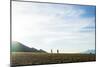 Two Men Walk Down A Ridge Line With A Dog Running Towards Them-Hannah Dewey-Mounted Photographic Print