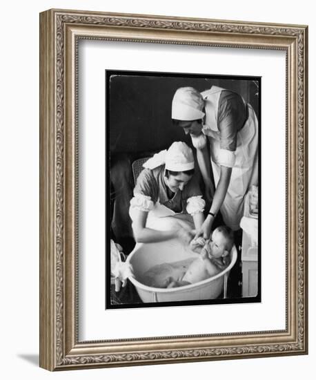 Two Nurses Bath a Baby-null-Framed Art Print