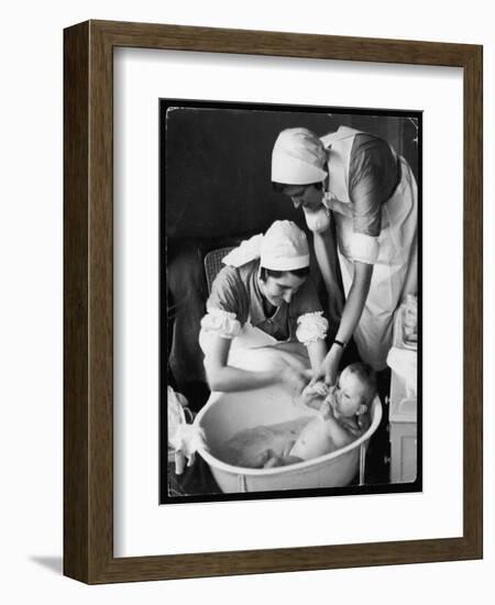 Two Nurses Bath a Baby-null-Framed Art Print