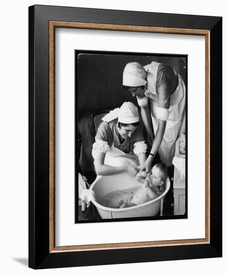 Two Nurses Bath a Baby-null-Framed Art Print