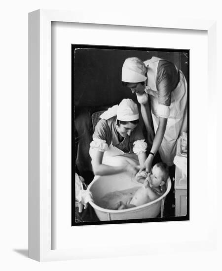 Two Nurses Bath a Baby-null-Framed Art Print