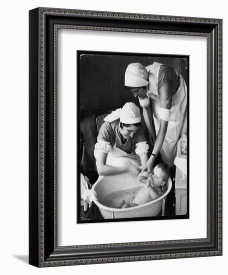 Two Nurses Bath a Baby-null-Framed Art Print