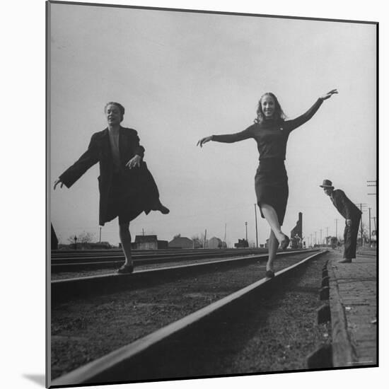 Two Young Ballet Russe Dancers Balancing on the Railroad Tracks in the Station While on Tour-Myron Davis-Mounted Photographic Print