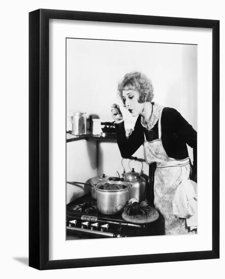 Young Woman in an Apron in Her Kitchen Tasting Her Food from a Pot-null-Framed Photo