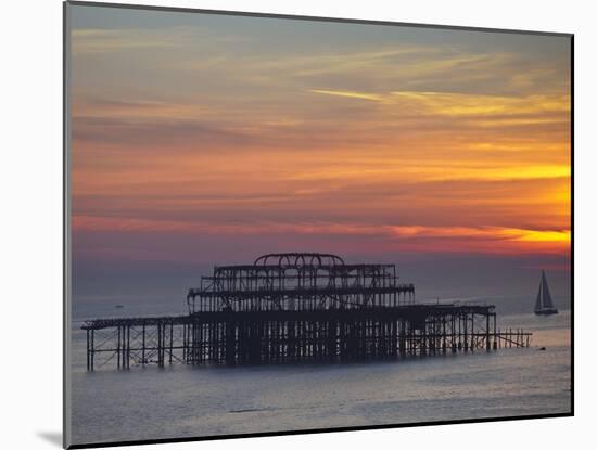 UK, England, Sussex, Brighton, Boat Sailing Past Remains of Brighton West Pier at Sunset-Jane Sweeney-Mounted Photographic Print