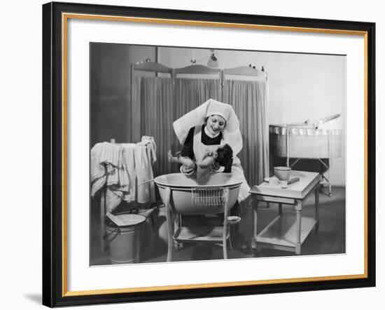 Uniformed Nurse Bathes a Baby in Hospital--Framed Photographic Print
