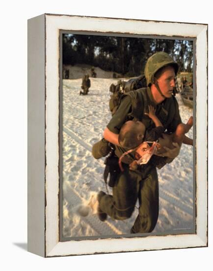 US Marine Medic Running Along Beach with Injured Vietnamese Infant under Fire During Vietnam War-Paul Schutzer-Framed Premier Image Canvas