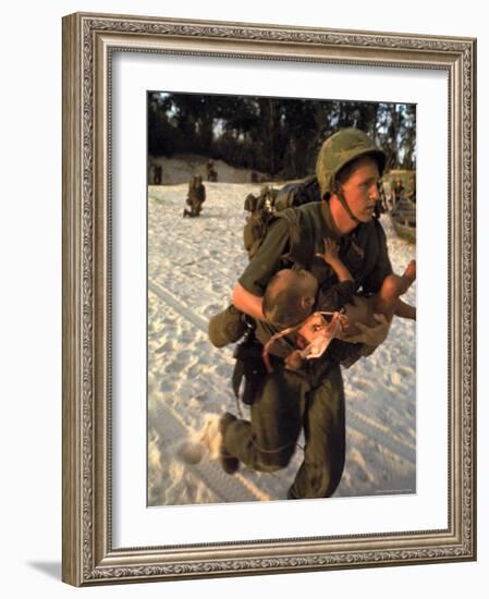 US Marine Medic Running Along Beach with Injured Vietnamese Infant under Fire During Vietnam War-Paul Schutzer-Framed Photographic Print