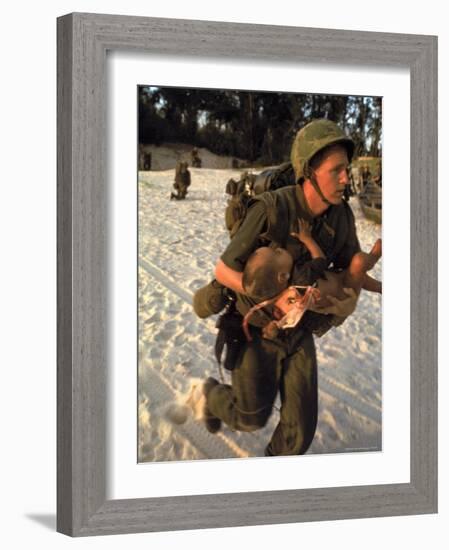 US Marine Medic Running Along Beach with Injured Vietnamese Infant under Fire During Vietnam War-Paul Schutzer-Framed Photographic Print