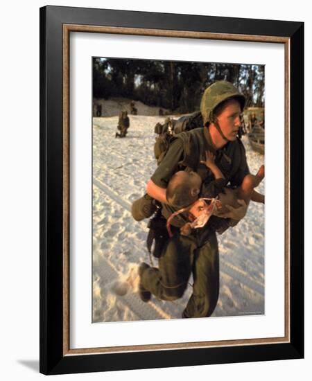 US Marine Medic Running Along Beach with Injured Vietnamese Infant under Fire During Vietnam War-Paul Schutzer-Framed Photographic Print