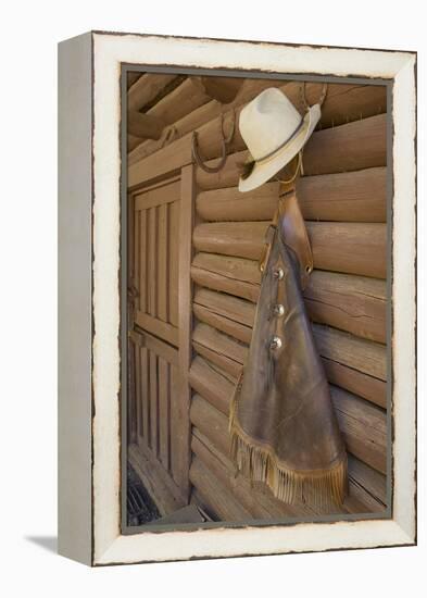 USA, Montana, Livingston, cowboy hat and chaps hanging on barn wall.-Merrill Images-Framed Premier Image Canvas