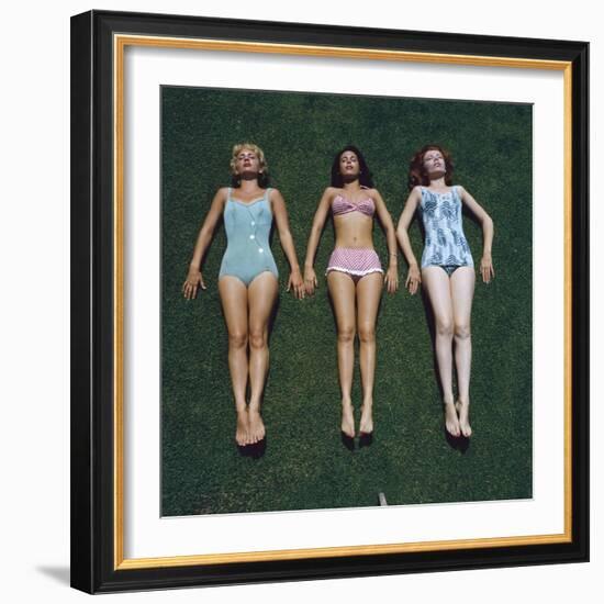 View of Three Unidentified Women in Bathing Suits as They Sunbath on Green Grass, 1961-Allan Grant-Framed Photographic Print