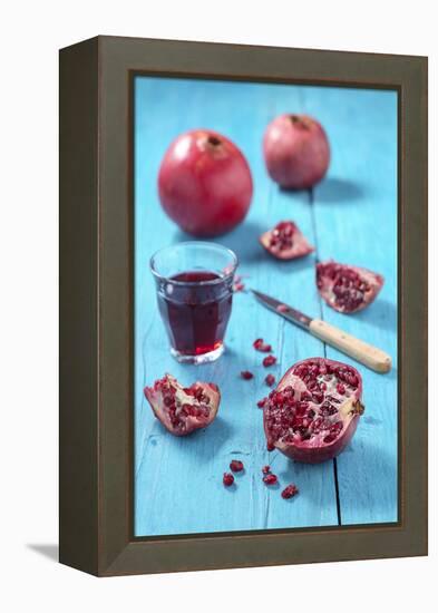 Whole and Sliced Pomegranate and Glass of Pomegranate Juice on Turquoise Wooden Table-Jana Ihle-Framed Premier Image Canvas