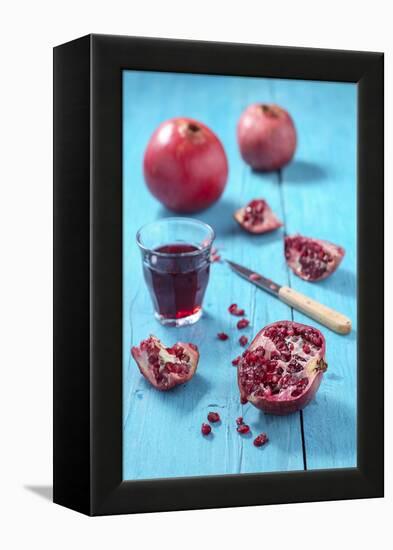 Whole and Sliced Pomegranate and Glass of Pomegranate Juice on Turquoise Wooden Table-Jana Ihle-Framed Premier Image Canvas